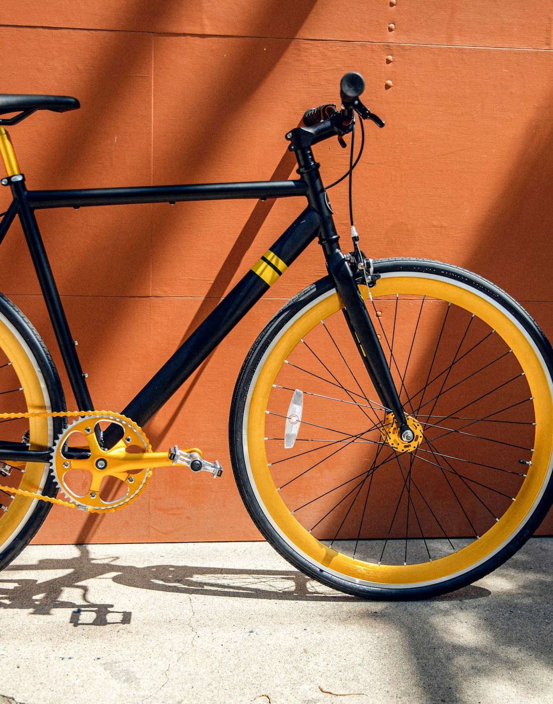 Bike urbana de aro amarelo encostada em parede laranja